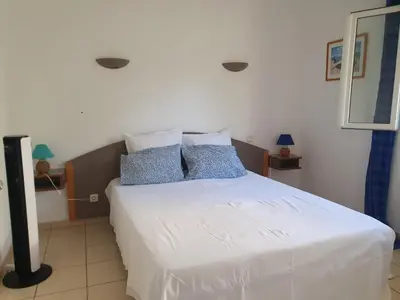 a bedroom with a large white bed with blue pillows at Appartement T2 bord de plage in Sartène
