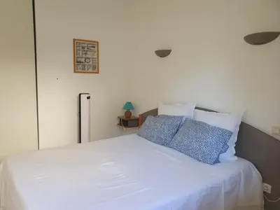 a white bed with two blue pillows on it at Appartement T2 bord de plage in Sartène