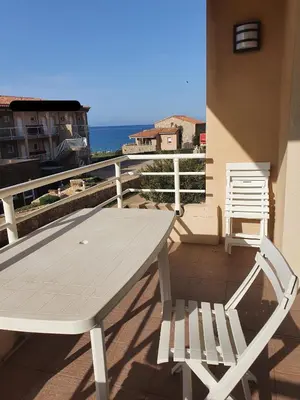 a white table and chairs on a balcony with the ocean at Appartement T2 bord de plage in Sartène