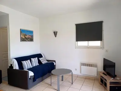 a living room with a blue couch and a tv at Appartement T2 bord de plage in Sartène