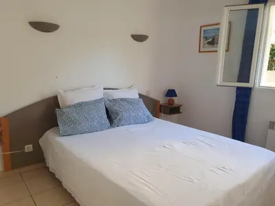 a bedroom with a white bed with blue pillows at Appartement T2 bord de plage in Sartène