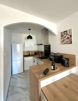 a kitchen with a refrigerator and a table in it at T2 hyper centre ville in Ajaccio