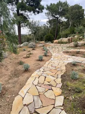 a stone path in a garden with trees in the background at Villa privée-piscine-vue mer-pinarello-cirindinu in Zonza