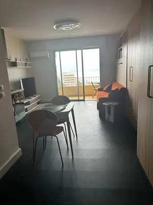 a living room with a table and chairs and a couch at Studio climatisé belle vue mer in Ajaccio