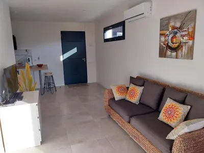 a living room with a couch and a blue door at Magnifique appartement entre mer et montagne in Tiuccia