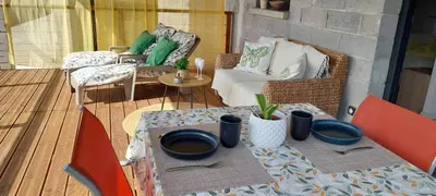 a patio with a table with bowls and utensils at Magnifique appartement entre mer et montagne in Tiuccia