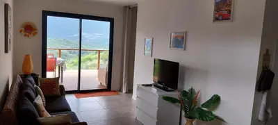 a living room with a television and a balcony at Magnifique appartement entre mer et montagne in Tiuccia