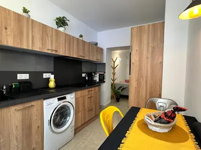 a kitchen with a washing machine and a table with yellow chairs at Magnifique deux pièces au cœur d Ajaccio in Ajaccio