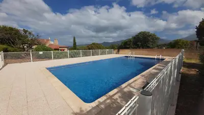 a swimming pool with blue water in a backyard at Appartement Papillon avec Piscine et Vue Mer in Propriano