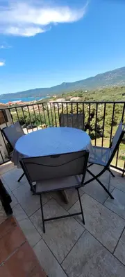 a table and chairs on a balcony with the ocean at Appartement Papillon avec Piscine et Vue Mer in Propriano