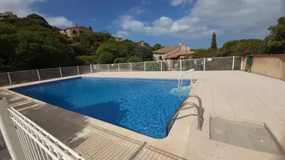 a large blue swimming pool in a backyard at Appartement Papillon avec Piscine et Vue Mer in Propriano