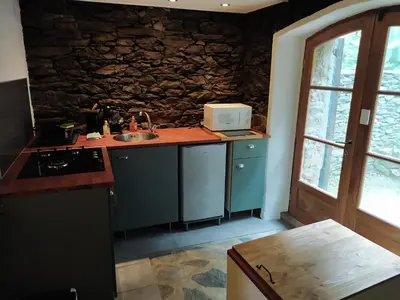 a kitchen with blue cabinets and a stone wall at Sole e Ventu in Velone-Orneto