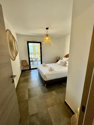 a bedroom with a bed and a room with a table at Appartement confort vue mer in Propriano