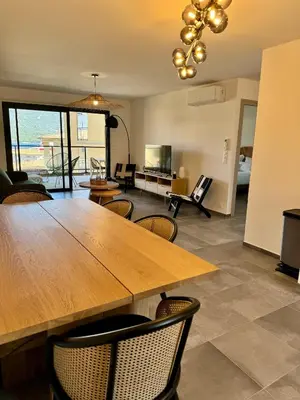 a dining room with a large wooden table and chairs at Appartement confort vue mer in Propriano