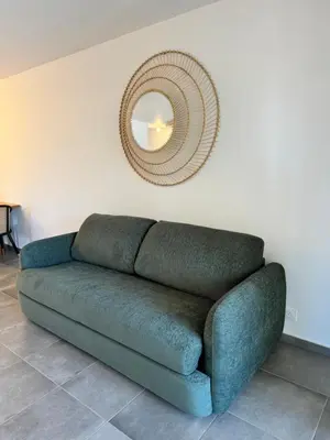 a green couch in a living room with a mirror at Appartement confort vue mer in Propriano