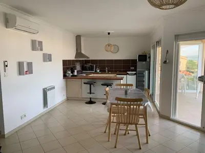 a kitchen and dining room with a table and chairs at Les Cistes Appt type 3 avec terrasse vue sur mer in Propriano