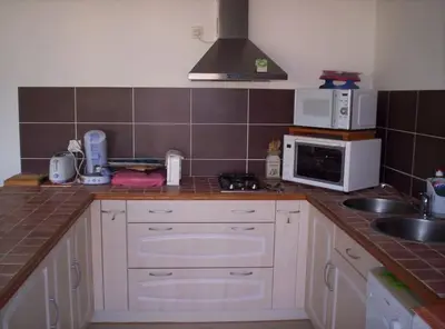 a kitchen with white cabinets and a sink and a microwave at Les Cistes Appt type 3 avec terrasse vue sur mer in Propriano
