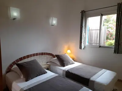 two beds in a room with a window at Villa EDEN BLUE in Zonza