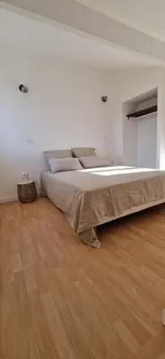 a large bed in a white room with a wooden floor at Studio folelli entre le centre et la plage in Penta-di-Casinca