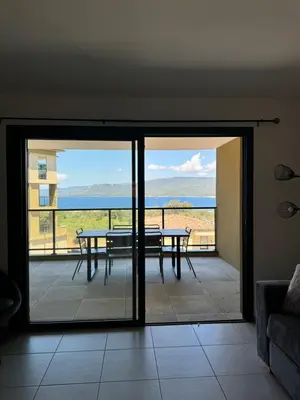 a room with a balcony with a table and a view at T3 de standing neuf vue mer in Propriano