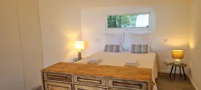 a bedroom with a bed with two lamps and a window at Villa U Caseddu - Vue mer, évasion et confort in Bonifacio