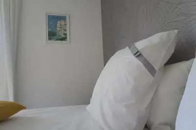 a white pillow on a bed with a picture on the wall at Casa Felicia in Bonifacio