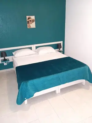 a bedroom with a large bed with a blue wall at Les villas de Melody in Santa-Maria-Poggio