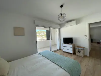 a white bedroom with a bed and a television at T2 neuf port de Bonifacio avec parking privé in Bonifacio