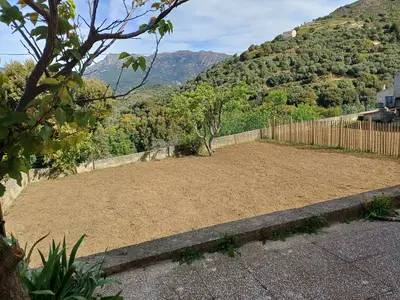 a large dirt yard with a fence and mountains at Maison à 15 minutes de Propriano in Santa-Maria-Figaniella