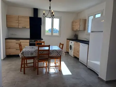 a kitchen with a table and chairs and a refrigerator at Maison à 15 minutes de Propriano in Santa-Maria-Figaniella