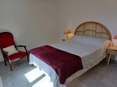 a bedroom with a bed and a red chair at Maison à 15 minutes de Propriano in Santa-Maria-Figaniella