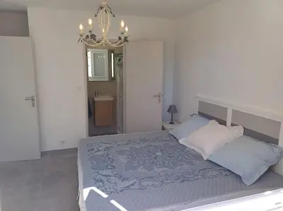 a bedroom with a bed and a chandelier at Maison à 15 minutes de Propriano in Santa-Maria-Figaniella
