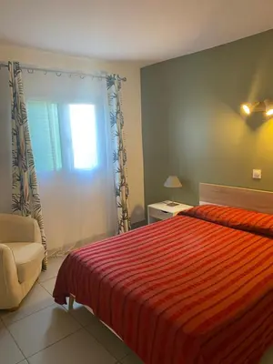 a bedroom with a bed and a chair and a window at Résidence 