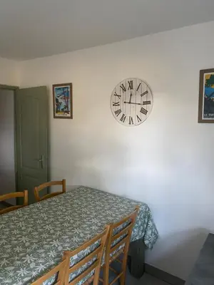 a clock on a white wall next to a table at Résidence 