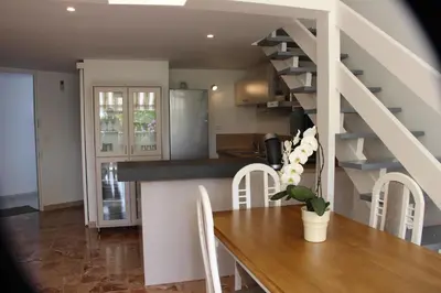 a kitchen and dining room with a table and a staircase at Duplex à 100 m de la plage in Grosseto-Prugna