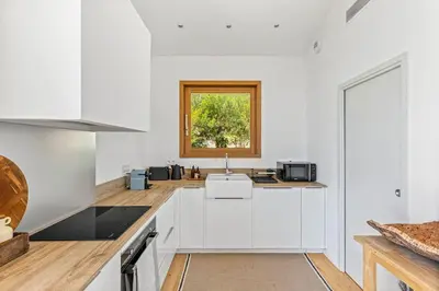 a white kitchen with a sink and a window at Villa A Grana in Zonza