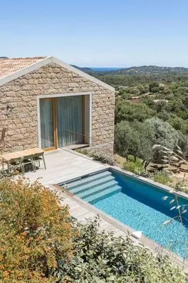a stone house with a swimming pool and a table at Villa A Grana in Zonza