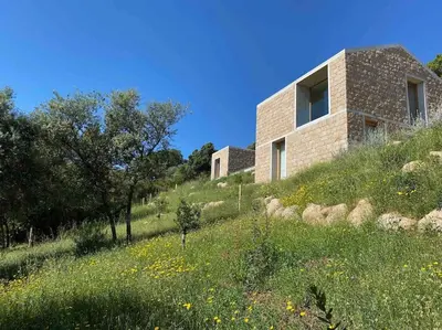 a brick house on a hill with a field of flowers at Villa A Grana in Zonza