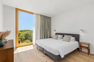 a bedroom with a large bed and a large window at Villa A Grana in Zonza