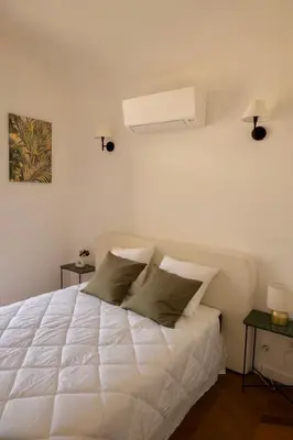 a white bed in a white room with two tables at Liviamariasanta in Ajaccio