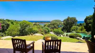 a patio with two chairs and a view of the ocean at Villa Capicciola, 8 pers, piscine, 30 m plage in Cirendinu