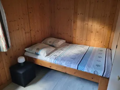 a small bed in a wooden room with a table at Chalet Cosy - U Nestru in Olmeto