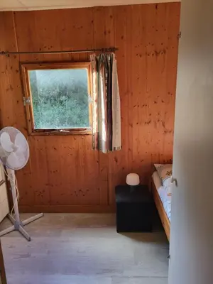 a room with a window and a bed and a fan at Chalet Cosy - U Nestru in Olmeto