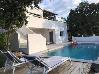 a swimming pool with chairs and a house at Villa Taru Pinarello in Mangialla