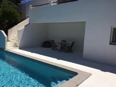 a white house with a table and a swimming pool at Villa Taru Pinarello in Mangialla