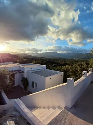 a view of a white house with mountains in the background at Villa Taru Pinarello in Mangialla