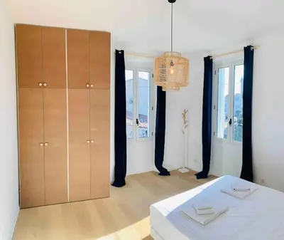 a bedroom with a bed and a cabinet and windows at Grand logement standing centre ville Porto-Vecchio in Porto-Vecchio
