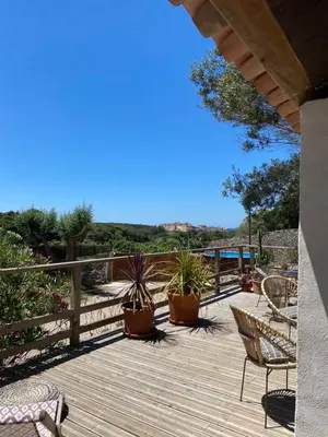 a wooden deck with chairs and potted plants on it at La Carpa in Bonifacio