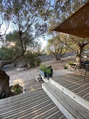 a wooden deck with a table and chairs and trees at La Carpa in Bonifacio