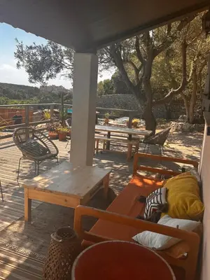 a porch with a table and chairs and a bench at La Carpa in Bonifacio